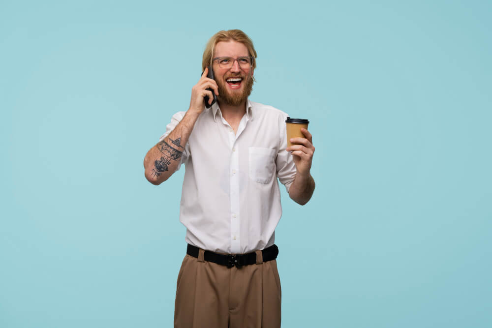 Glad snubbe snackar i mobiltelefon med billigt kaffe i handen